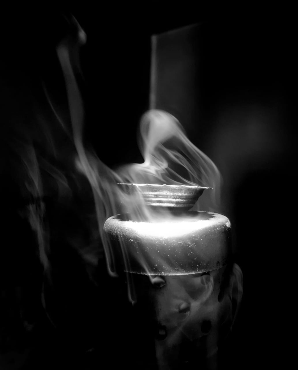 Incense stick holder with rising smoke in a dark setting